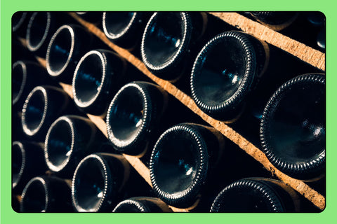Bottles of wine stored horizontally on a wooden shelf / wine rack.